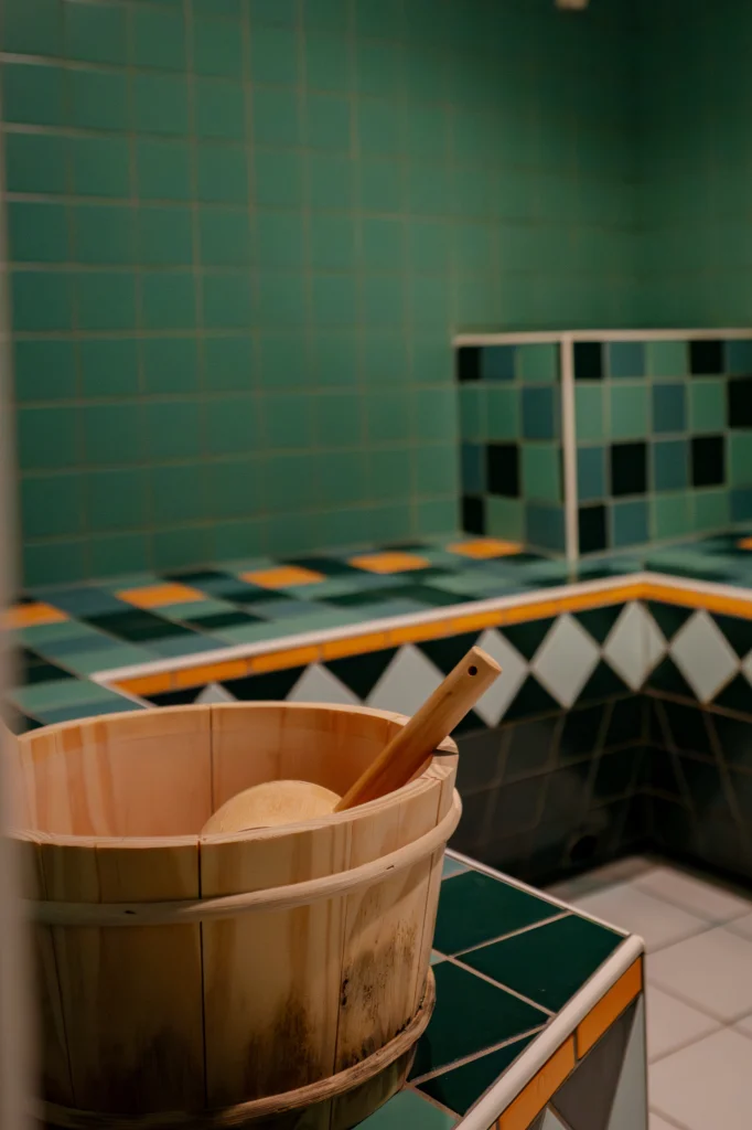 Hammam d’Izzy Spa à Verbier : banquettes en mosaïque verte et seau en bois